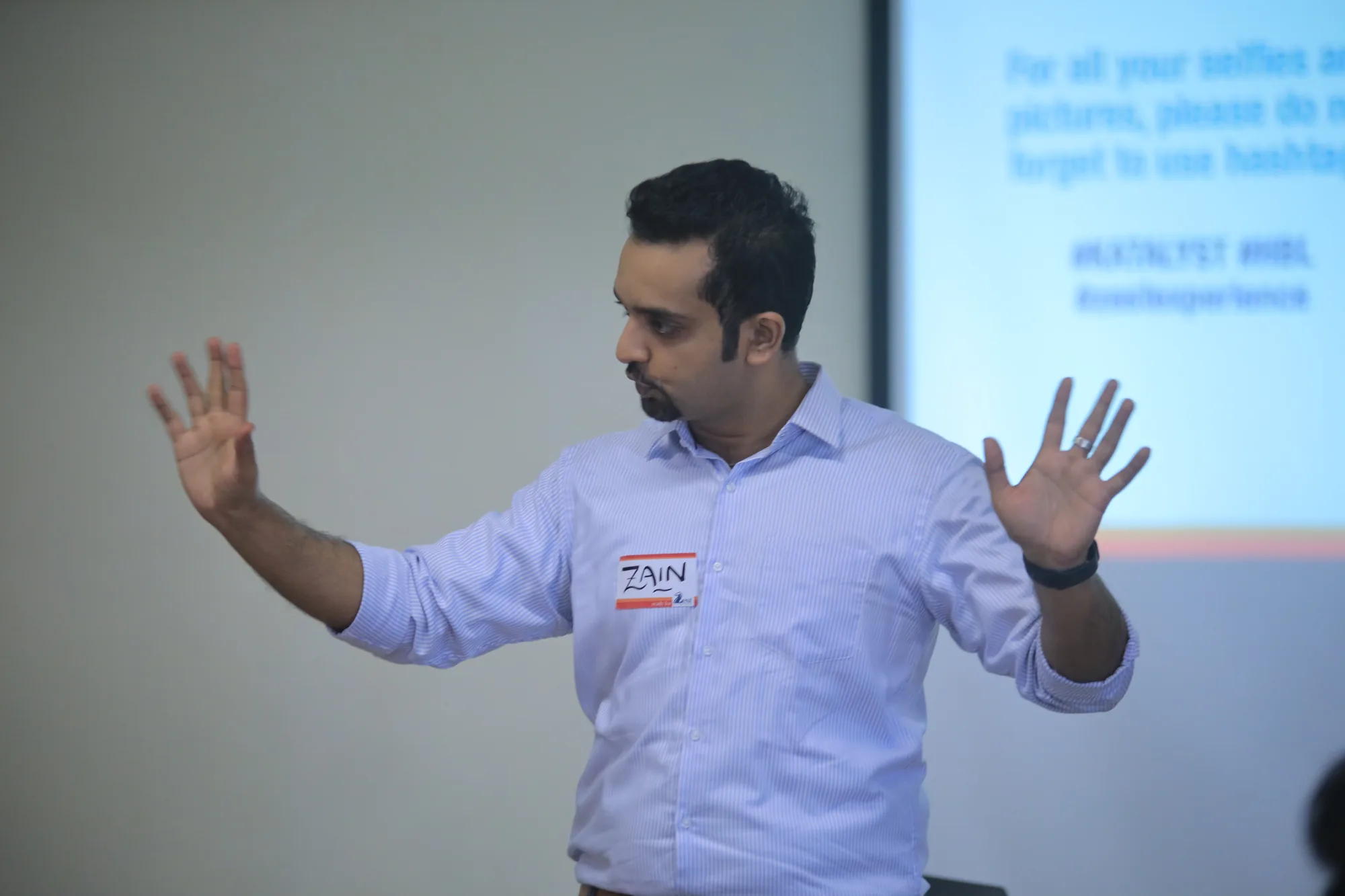 Zain Goplani, Founder of Zest Experience, facilitating a leadership workshop with both hands raised