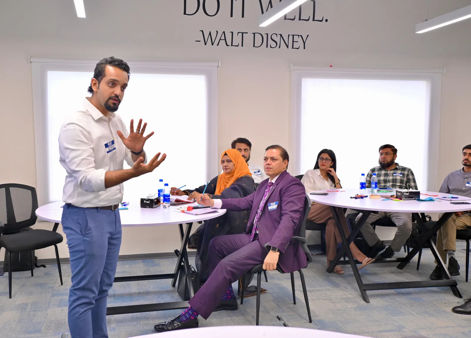 Zain Goplani facilitating a discussion with participants seated at round tables during a sales workshop